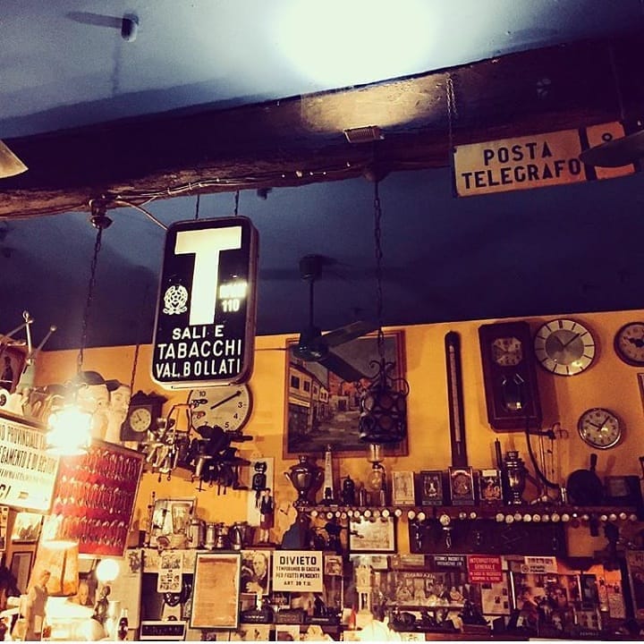 Interno dell'osteria con insegne d'epoca, vecchi orologi e memorabilia appesi alle travi